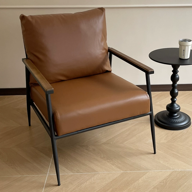 An Industrial-style Armchair With A Black Metal Frame, Wooden Armrests, and Tan Faux Leather Upholstery